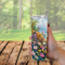 Woman holding floral beach tumbler outdoors at sunny table